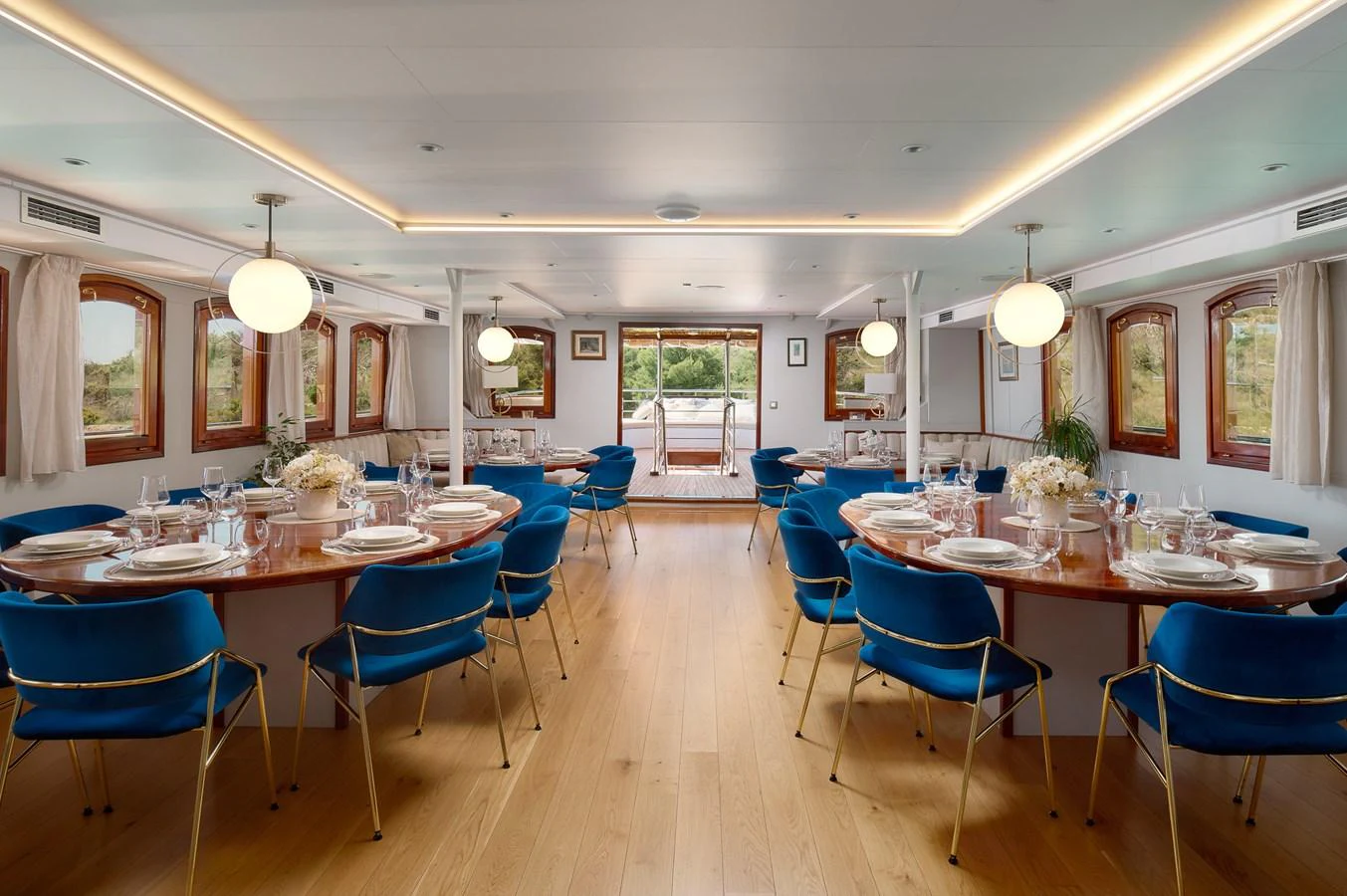 The yacht's dining area features elegant table settings and plush blue chairs, creating a refined atmosphere for meals. aboard BELLEZZA Yacht for Sale
