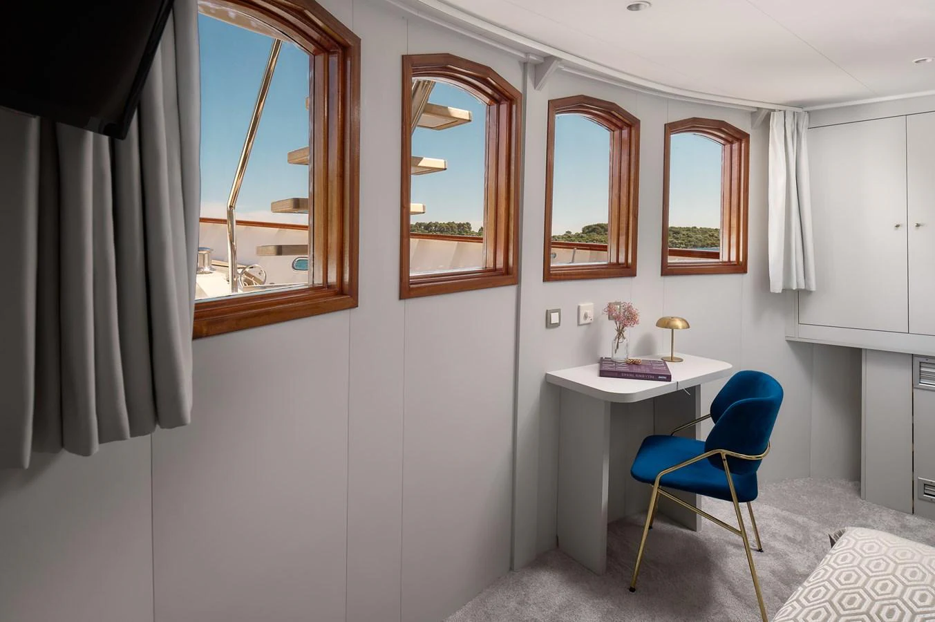 A cozy stateroom with a desk and a view through multiple windows. aboard BELLEZZA Yacht for Sale