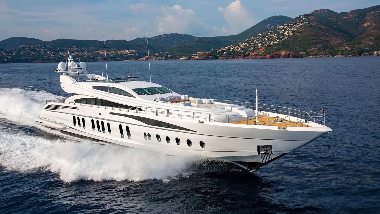 A sleek and modern yacht cruising swiftly on the open water with a scenic coastline in the background. aboard D'ONE D Yacht for Sale