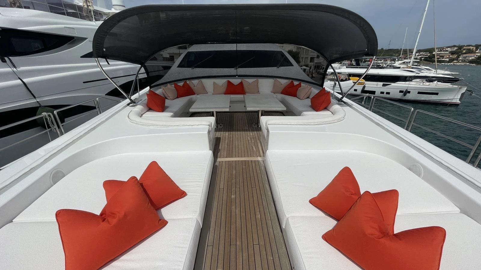 The sundeck features plush white seating with vibrant orange cushions, shaded by a sleek canopy. aboard D'ONE D Yacht for Sale