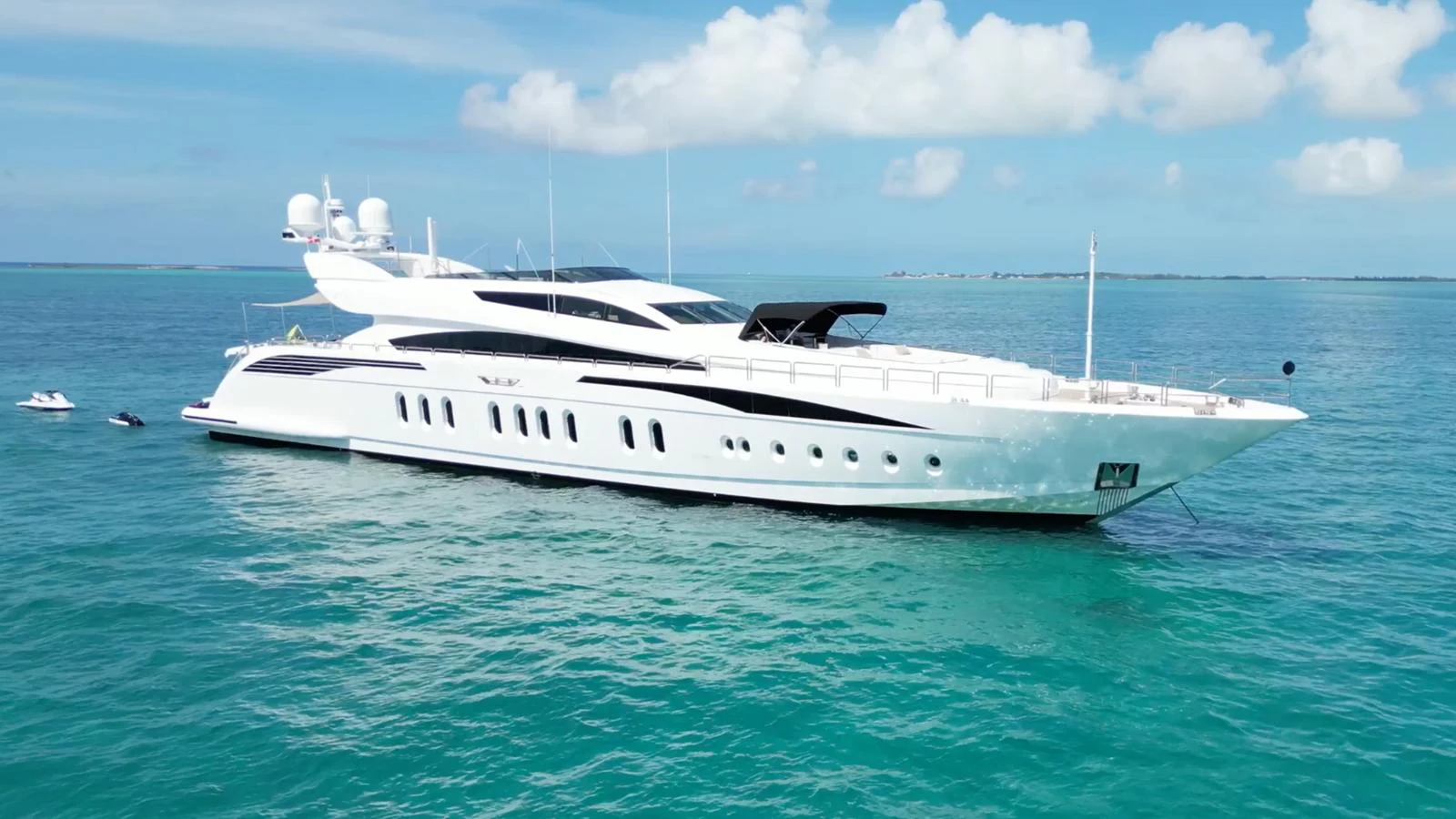 A sleek and modern yacht cruising on clear turquoise waters under a bright blue sky. aboard BET ON IT Yacht for Sale
