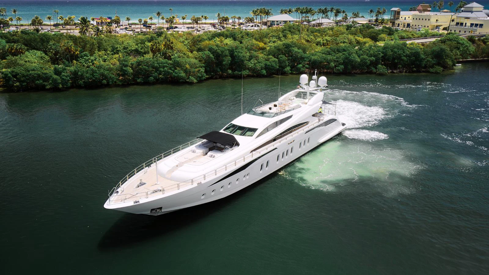 A sleek and modern yacht cruising through a serene waterway with lush greenery in the background. aboard BET ON IT Yacht for Sale