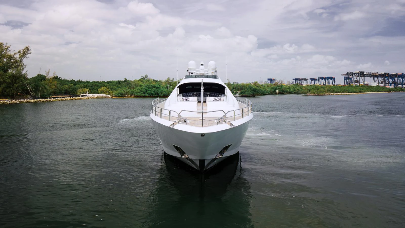 A sleek yacht is captured head-on, cruising through calm waters with a scenic backdrop. aboard BET ON IT Yacht for Sale