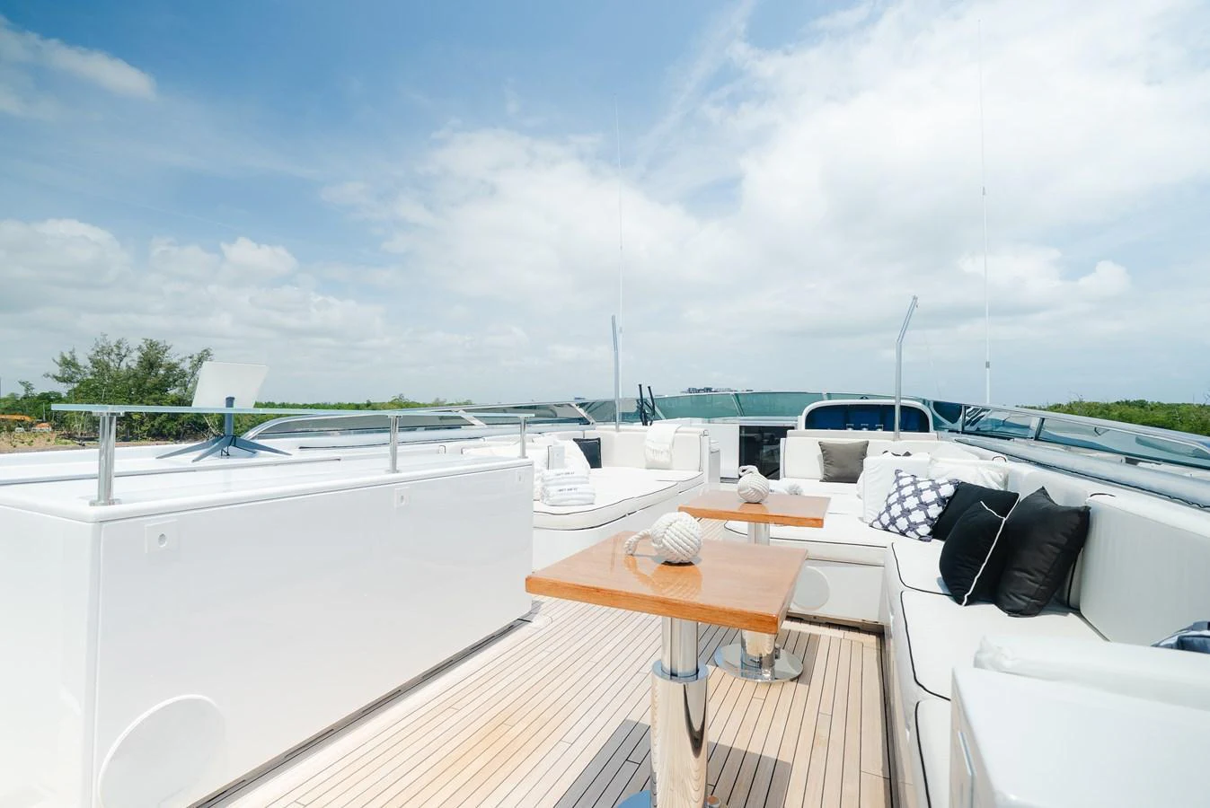 The sundeck offers a relaxing space with comfortable seating and a central table under a clear sky. aboard BET ON IT Yacht for Sale