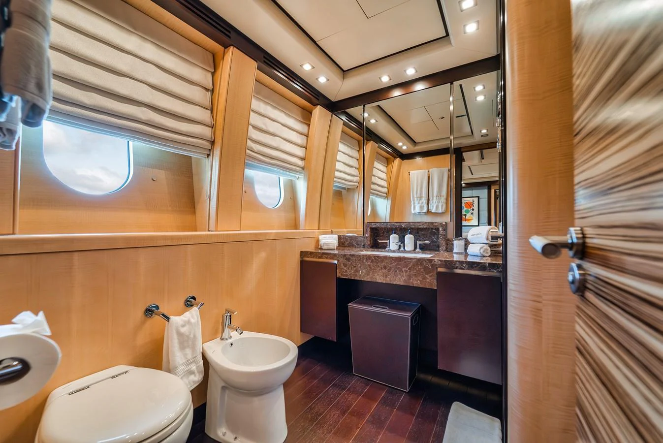 The yacht's bathroom features elegant wood finishes, a marble countertop, and ample natural light. aboard BET ON IT Yacht for Sale