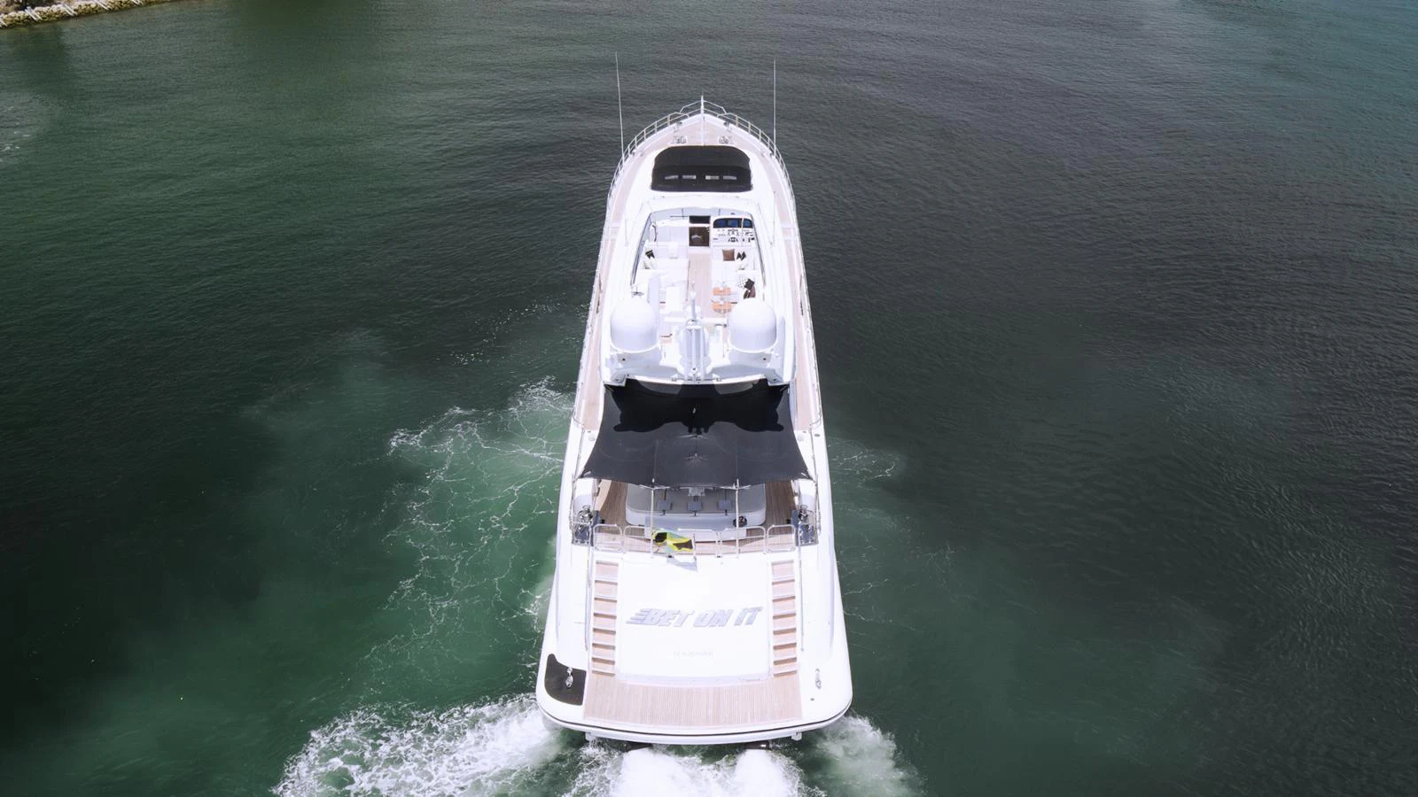 A sleek yacht cruises through calm waters, showcasing its spacious deck and modern design. aboard BET ON IT Yacht for Sale