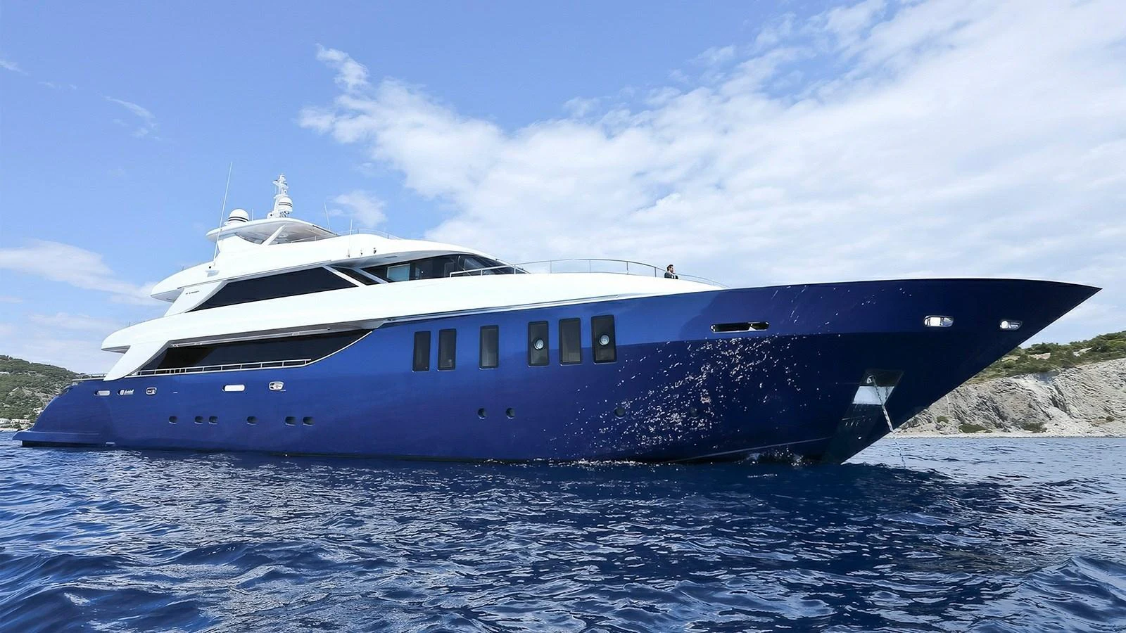 A sleek and modern yacht glides gracefully on the open water under a clear sky. aboard IPANEMAS Yacht for Sale