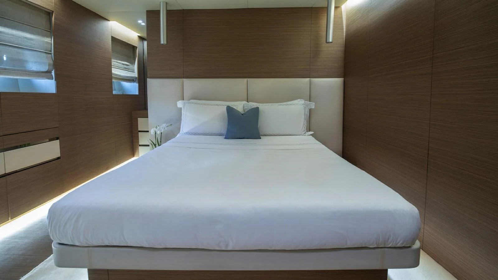 A luxurious stateroom featuring a large, comfortable bed with modern wooden paneling and soft lighting. aboard IPANEMAS Yacht for Sale