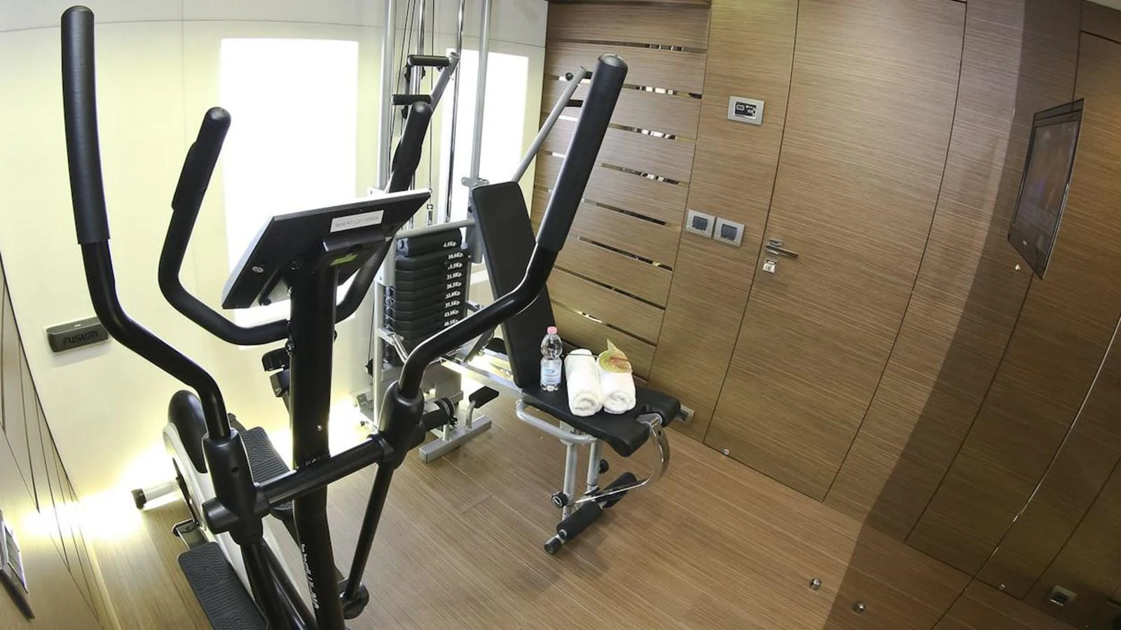 The yacht features a well-equipped gym with modern fitness equipment and a sleek, wooden interior. aboard IPANEMAS Yacht for Sale