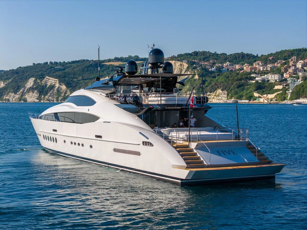 A sleek and modern yacht cruising along a picturesque coastline. aboard FIVE Yacht for Sale