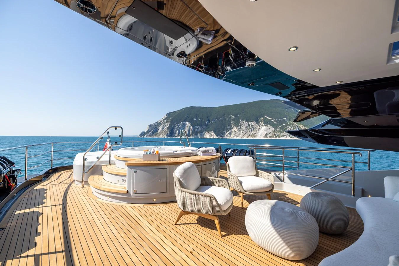 The aft deck features a spacious lounging area with comfortable seating and a jacuzzi, offering stunning views of the surrounding waters and cliffs. aboard FIVE Yacht for Sale