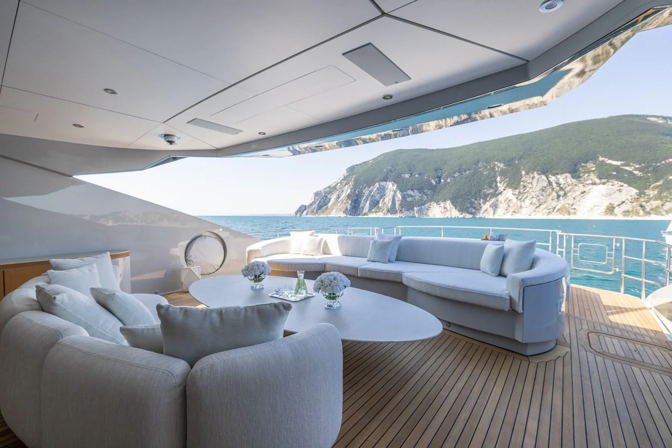 The aft deck features luxurious seating with stunning ocean and cliffside views. aboard FIVE Yacht for Sale