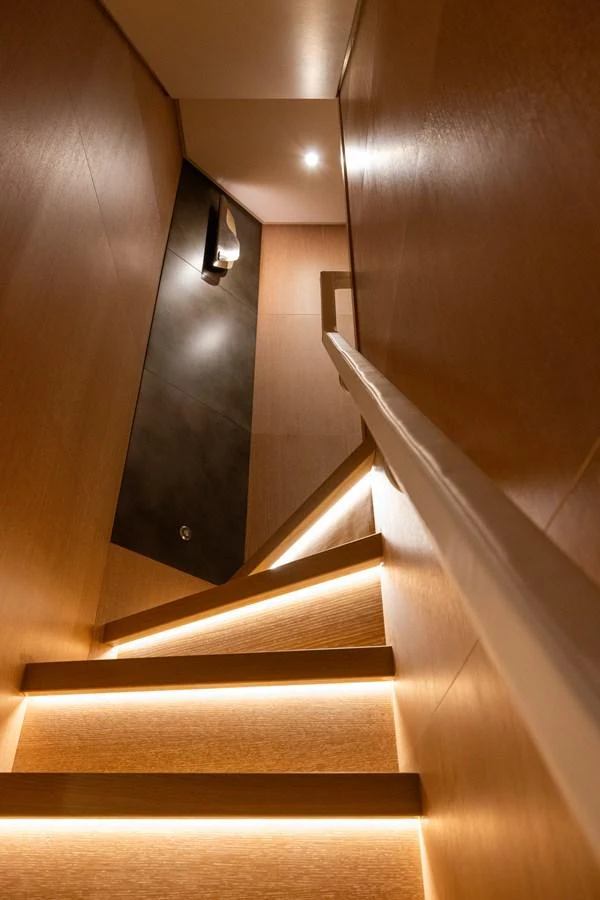 A modern staircase with ambient lighting leads to the lower deck. aboard FIVE Yacht for Sale