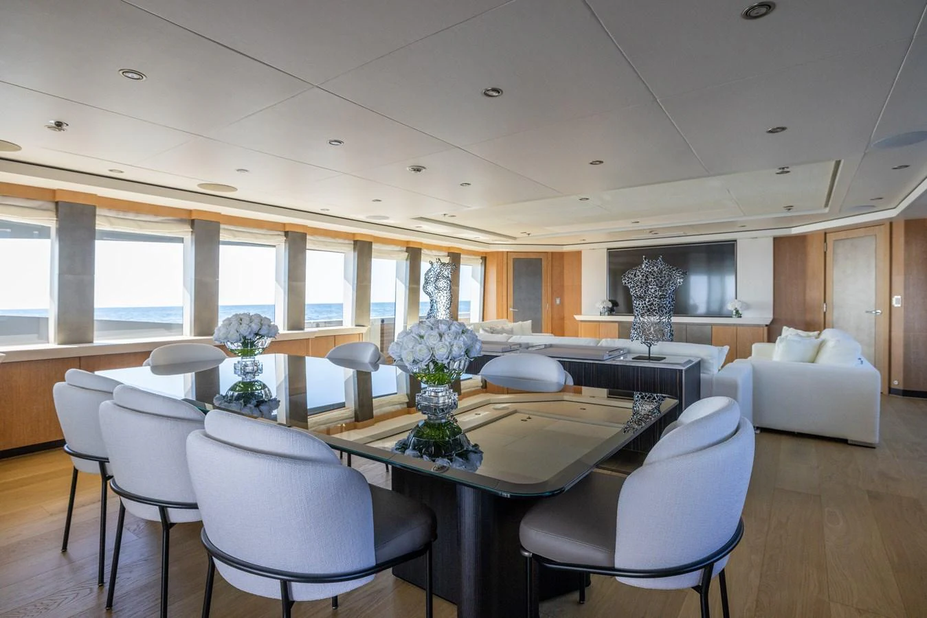 The spacious salon features elegant decor with ample seating and a dining area, offering panoramic views through large windows. aboard FIVE Yacht for Sale