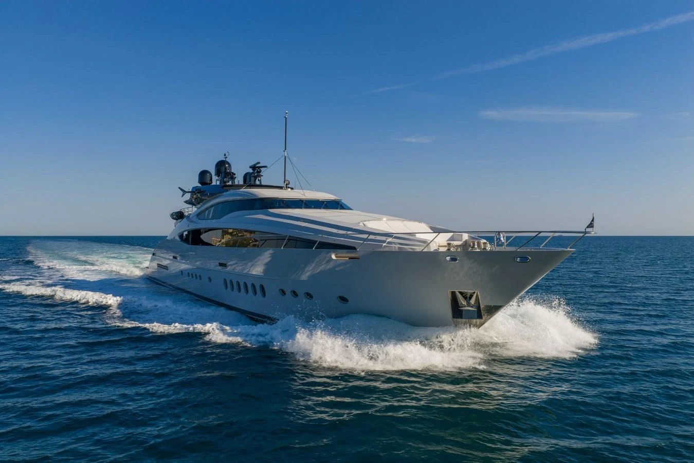 A sleek and modern yacht cruises swiftly through the open sea under a clear blue sky. aboard FIVE Yacht for Sale