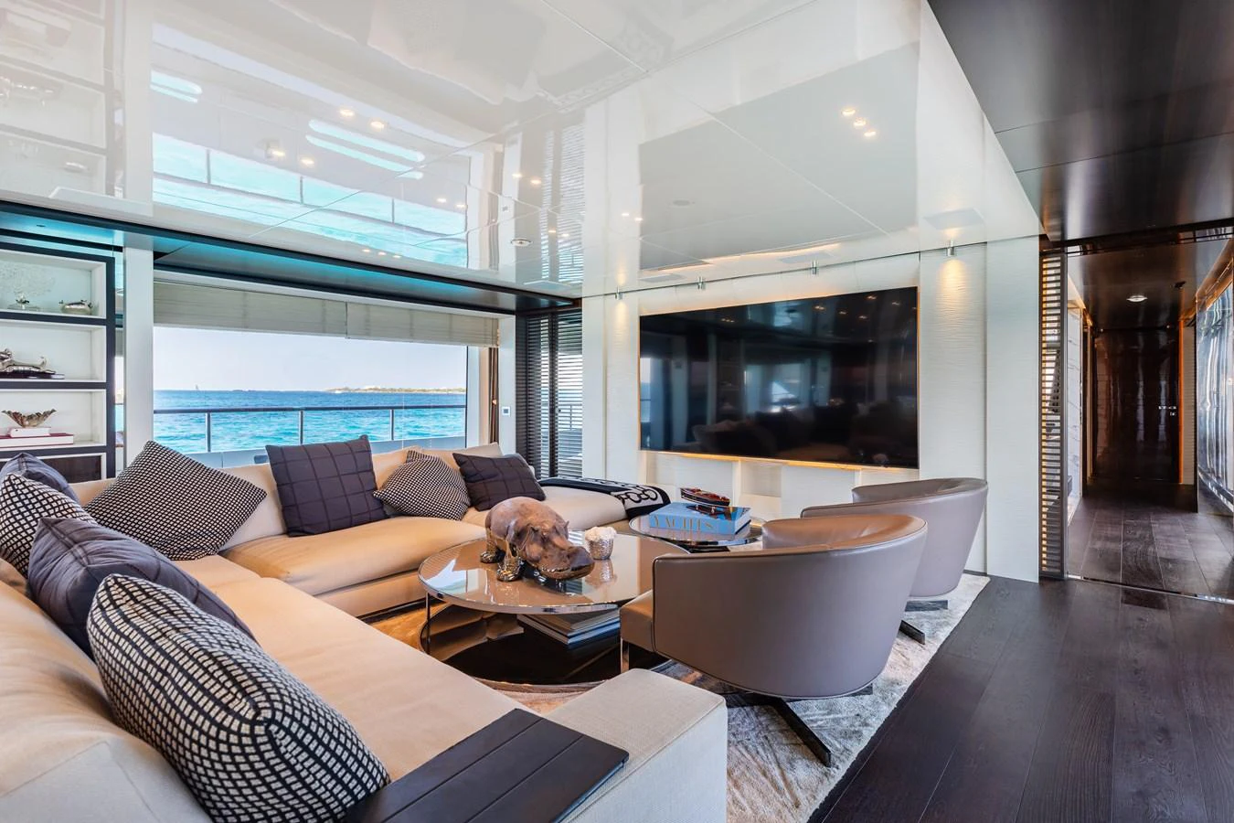 The salon features a spacious seating area with a large TV and panoramic ocean views. aboard DOMANI Yacht for Sale