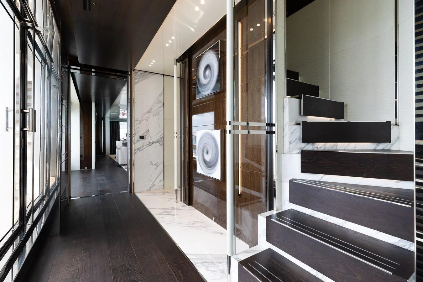 A luxurious interior featuring a modern staircase with dark wood steps and elegant marble accents. aboard DOMANI Yacht for Sale