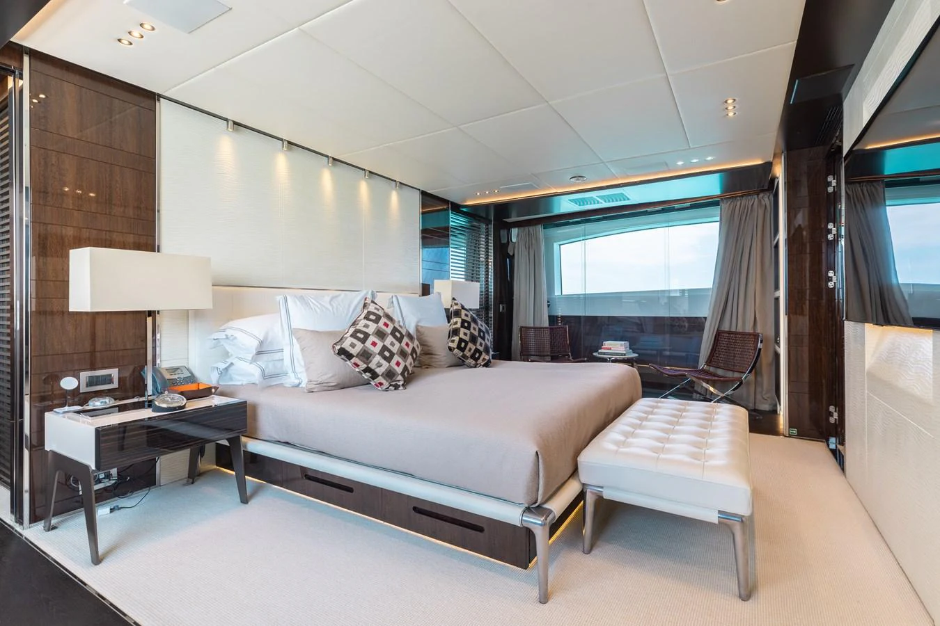 The master stateroom features a luxurious bed with elegant furnishings and a large window offering stunning views. aboard DOMANI Yacht for Sale