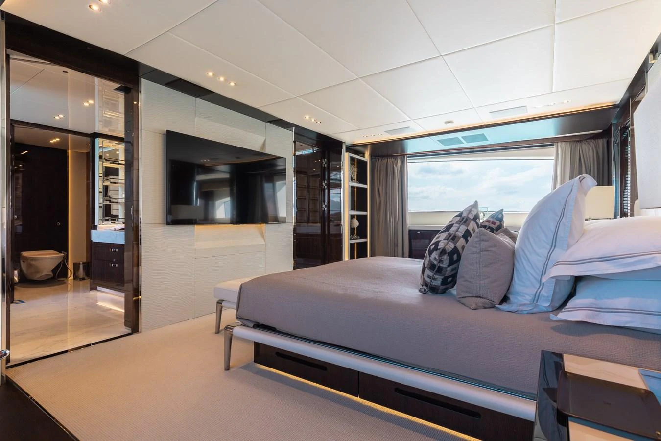 A luxurious stateroom featuring a large bed, modern decor, and a flat-screen TV. aboard DOMANI Yacht for Sale