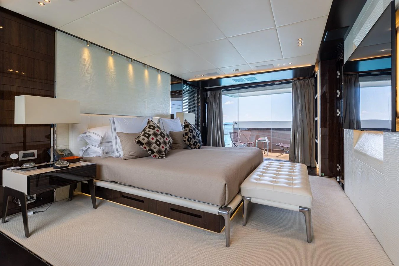 The master stateroom features a luxurious bed with elegant furnishings and a private balcony view. aboard DOMANI Yacht for Sale