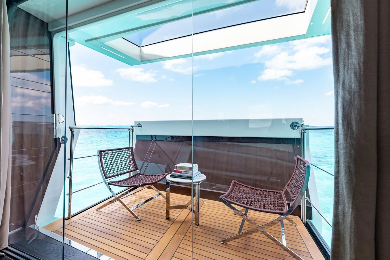 A serene yacht balcony with modern seating and a stunning ocean view. aboard DOMANI Yacht for Sale
