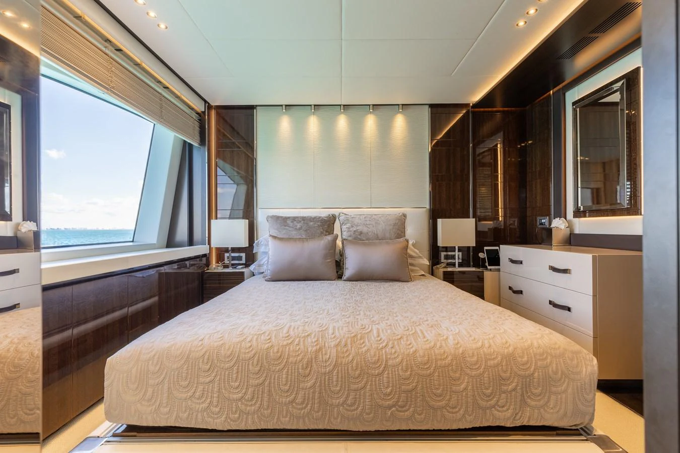 A luxurious stateroom featuring a large bed with elegant bedding and ample natural light from the window. aboard DOMANI Yacht for Sale