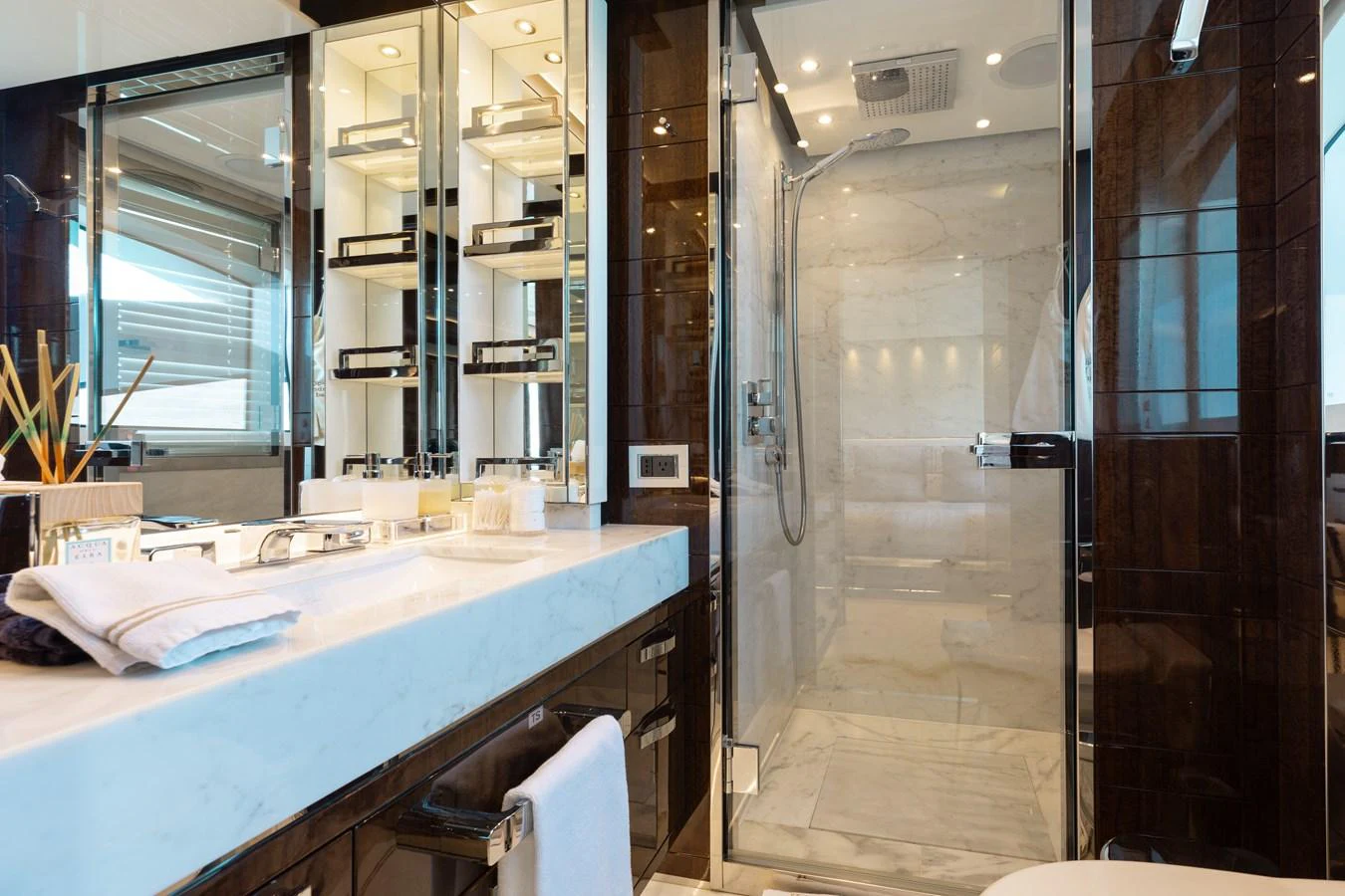 The yacht's bathroom features a luxurious marble countertop and a spacious glass-enclosed shower. aboard DOMANI Yacht for Sale