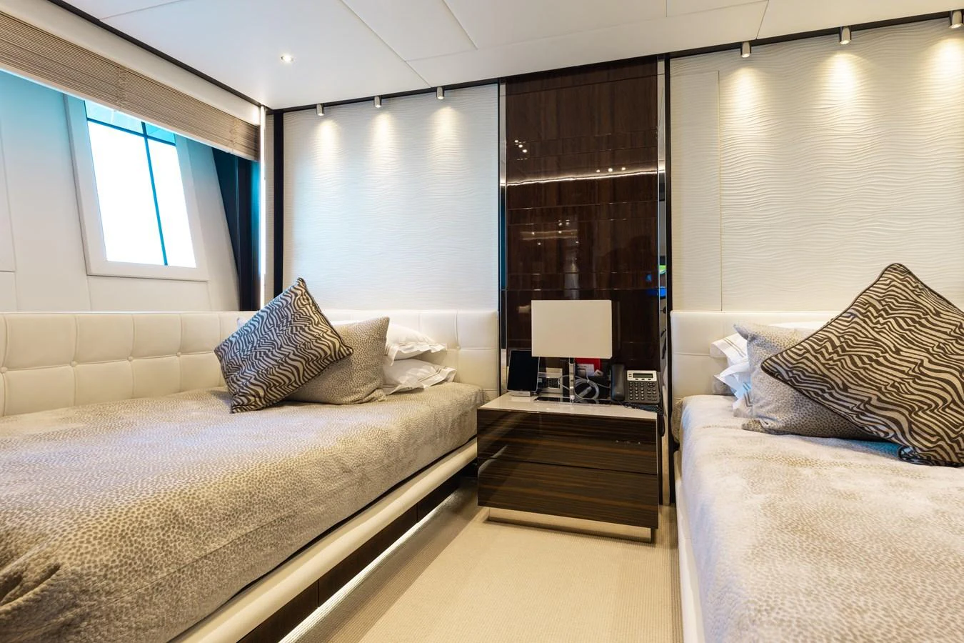 The guest stateroom features twin beds, modern decor, and ample lighting for a comfortable stay. aboard DOMANI Yacht for Sale