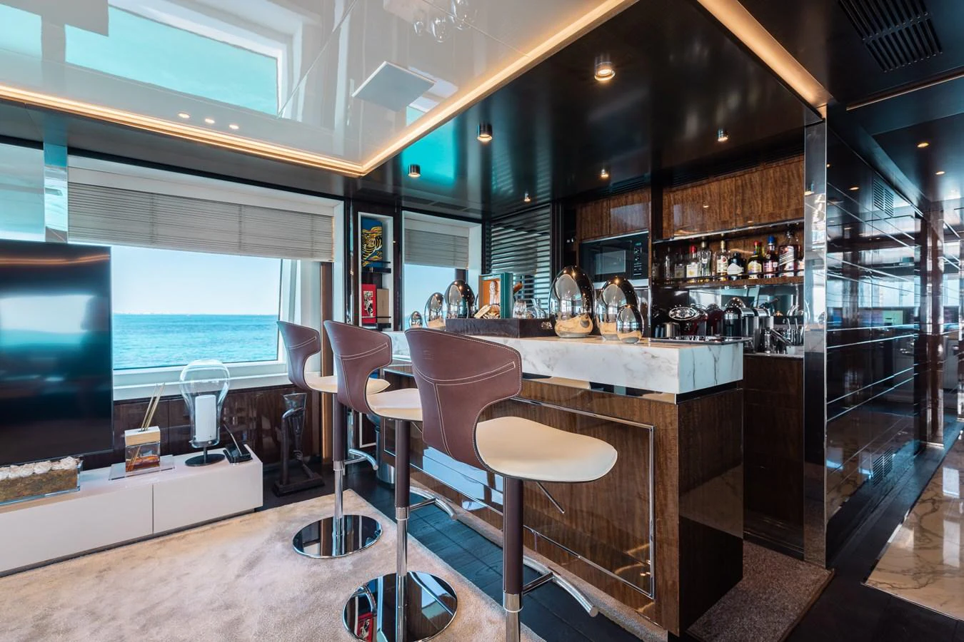 The yacht's interior features a sleek and modern bar area with a stunning ocean view. aboard DOMANI Yacht for Sale