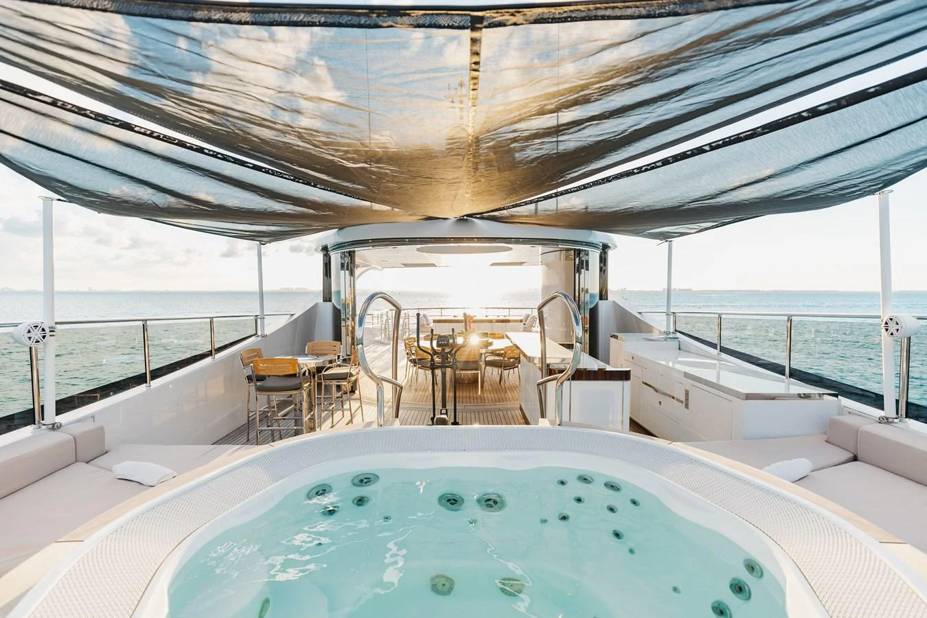 The sundeck features a luxurious jacuzzi with ample seating and dining areas, all under a stylish canopy. aboard DOMANI Yacht for Sale