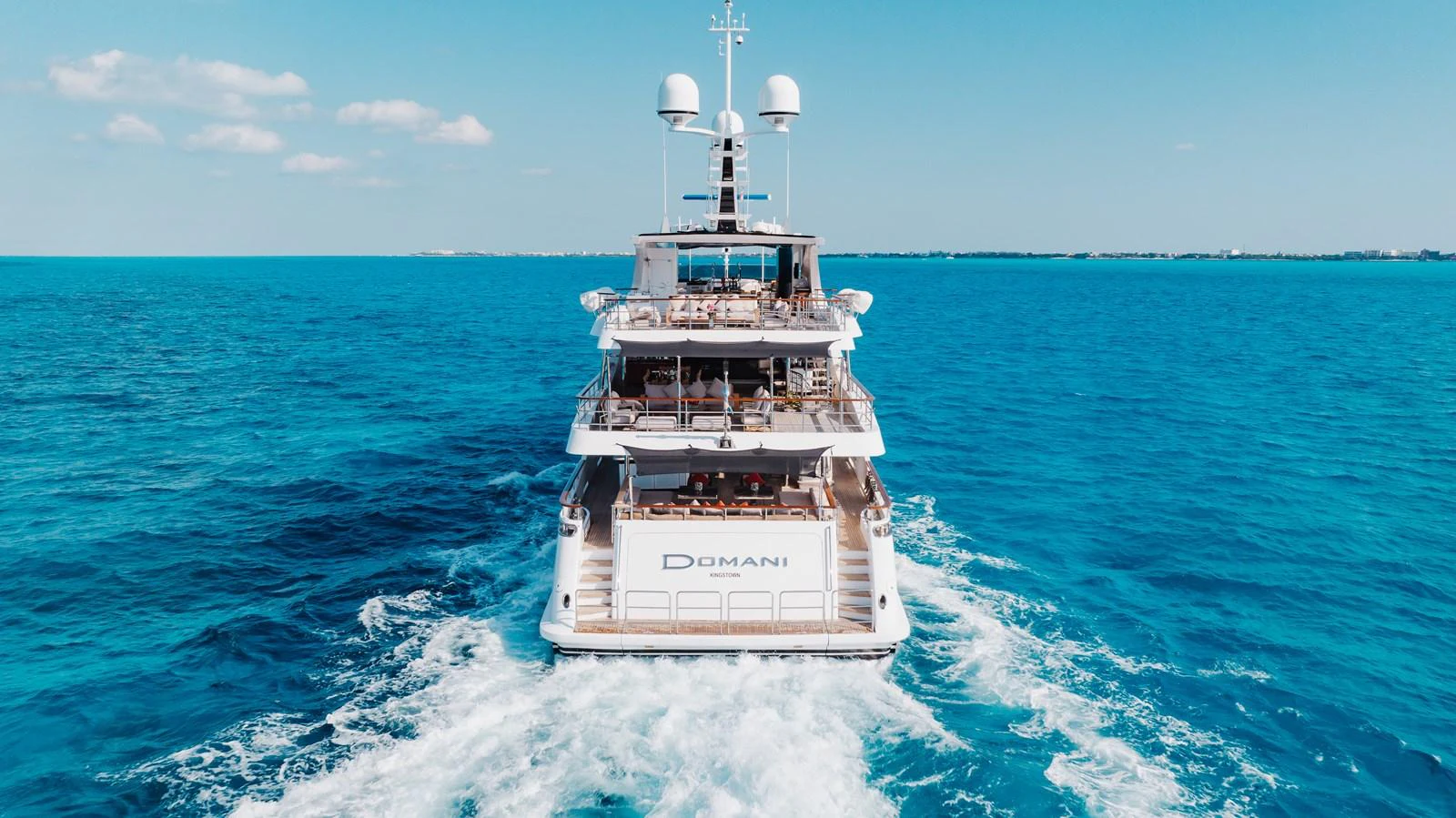 A luxurious yacht cruises through clear blue waters, showcasing its elegant design and spacious decks. aboard DOMANI Yacht for Sale