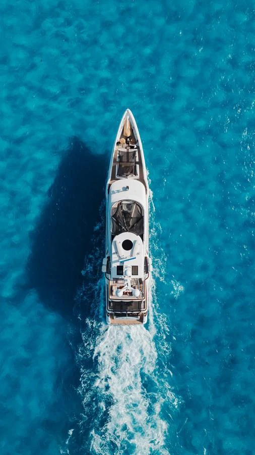 A stunning aerial view of a yacht cruising through clear blue waters. aboard DOMANI Yacht for Sale