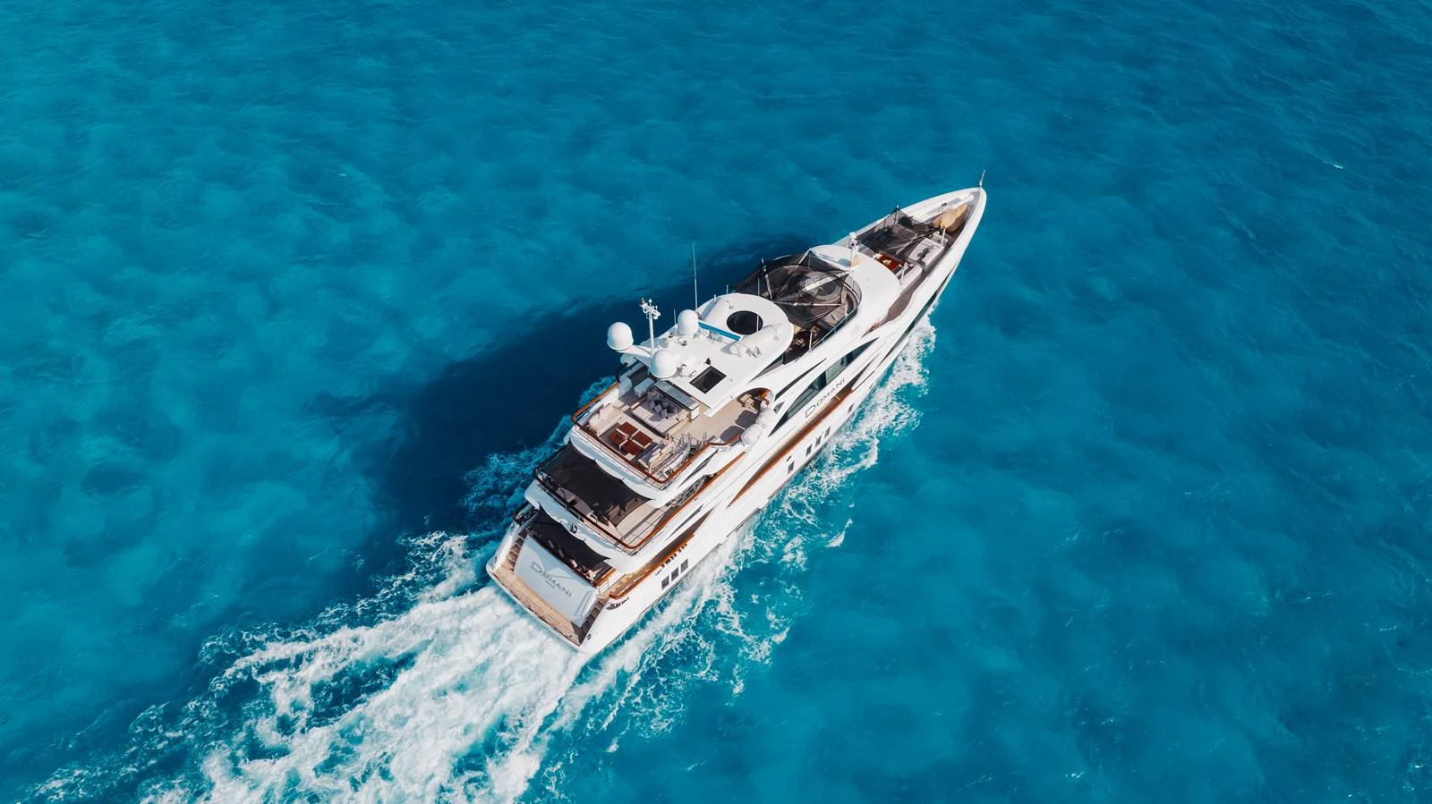 A luxurious yacht cruises through pristine blue waters, showcasing its elegant design and spacious decks. aboard DOMANI Yacht for Sale
