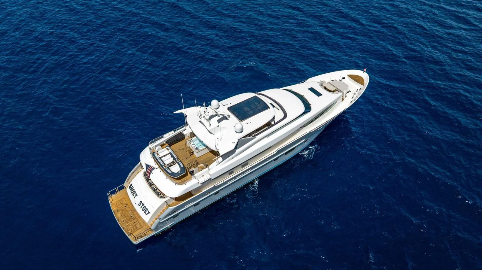 A sleek and luxurious yacht cruises through the deep blue sea, showcasing its elegant design and spacious decks. aboard SHORT STORY Yacht for Sale