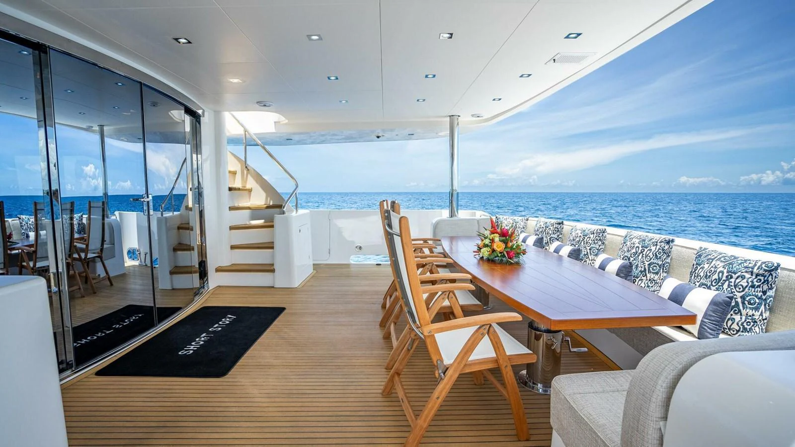 The aft deck offers a spacious and inviting area with a dining table and comfortable seating, perfect for enjoying meals with a stunning ocean view. aboard SHORT STORY Yacht for Sale