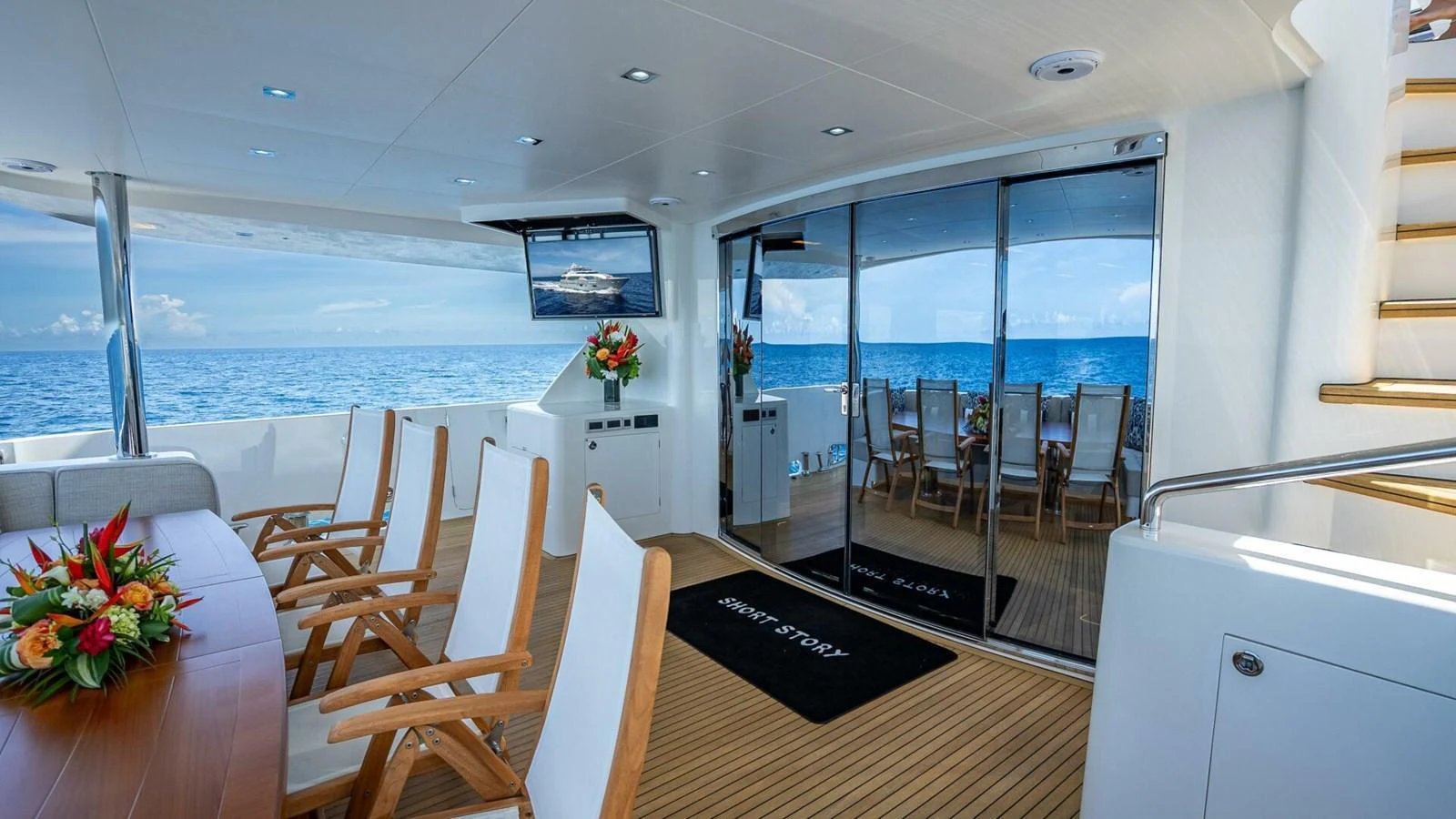 The aft deck features a spacious seating area with a dining table and chairs, offering stunning ocean views. aboard SHORT STORY Yacht for Sale