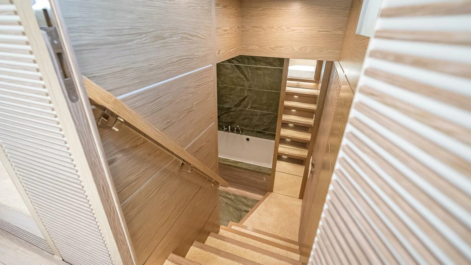 A modern wooden staircase leads down to a luxurious interior space. aboard SHORT STORY Yacht for Sale