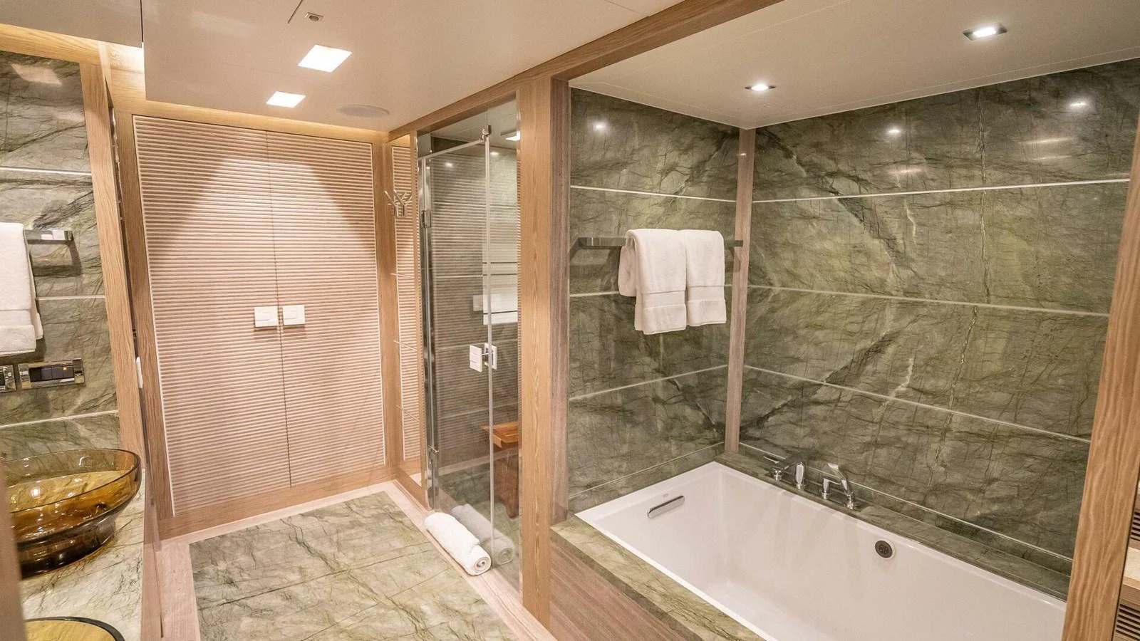 The yacht's bathroom features luxurious green marble walls and a spacious bathtub. aboard SHORT STORY Yacht for Sale