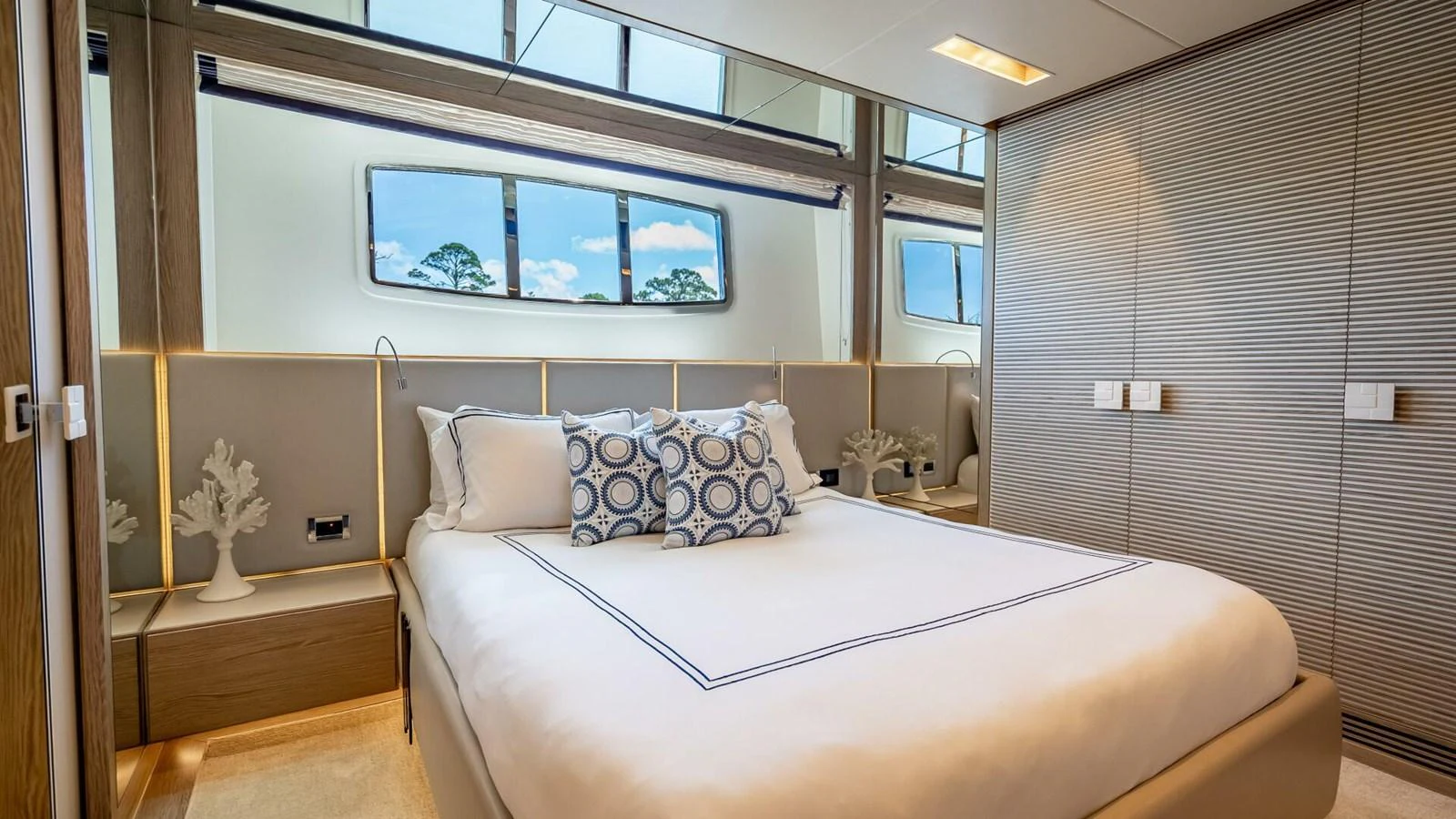 A luxurious stateroom featuring a plush bed with decorative pillows and large windows offering scenic views. aboard SHORT STORY Yacht for Sale
