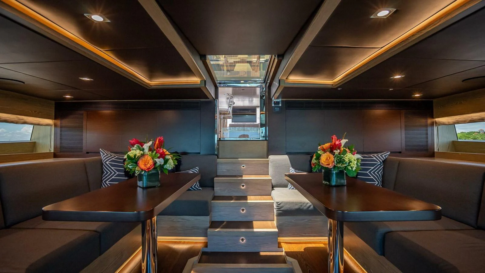 The yacht's saloon features elegant dark wood finishes, plush seating, and vibrant floral arrangements. aboard SHORT STORY Yacht for Sale
