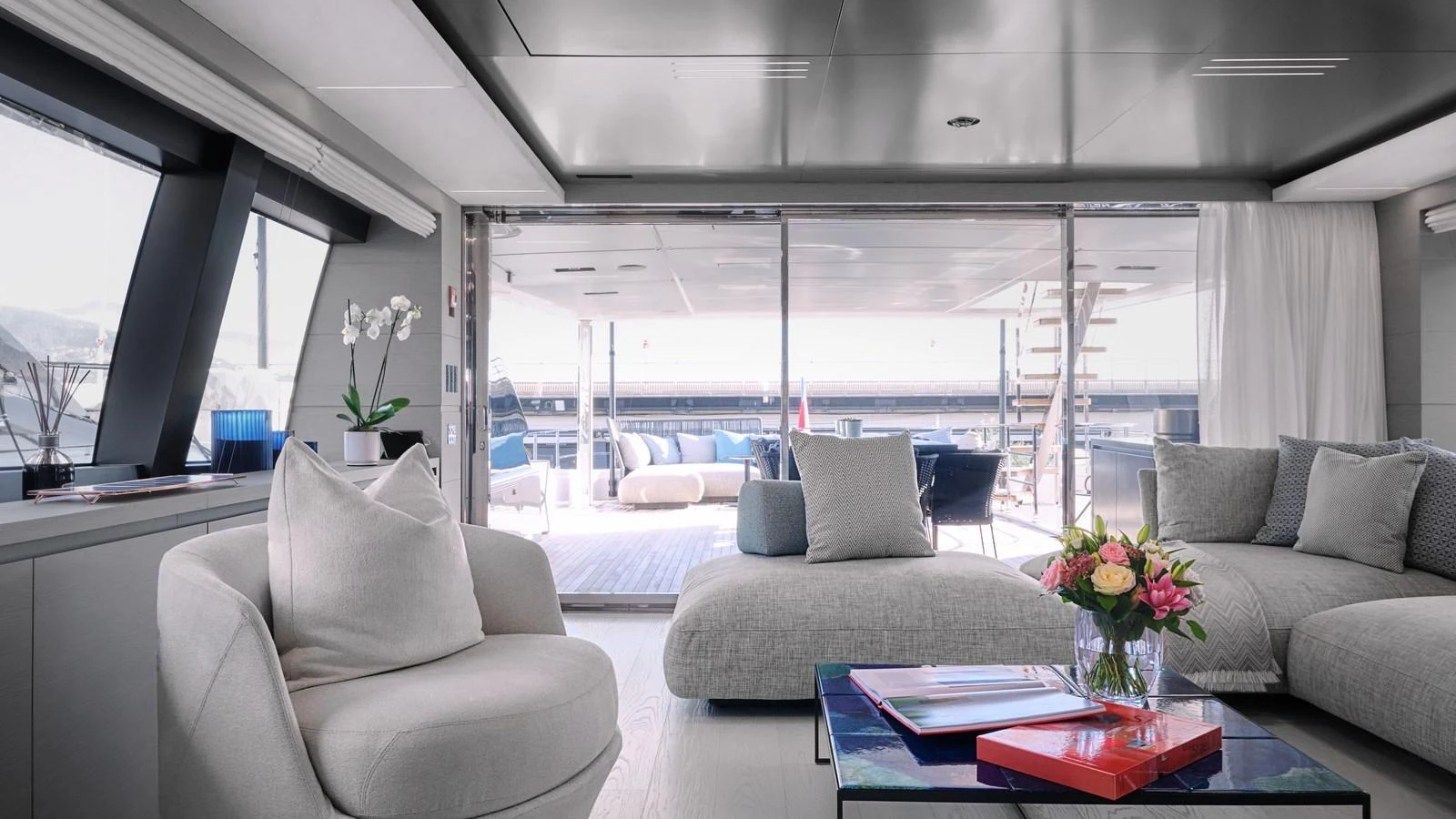 The yacht's interior features a modern and elegant lounge area with plush seating and a view of the aft deck. aboard BIZMAN Yacht for Sale