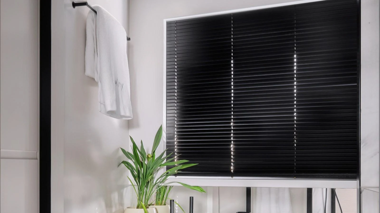 A modern yacht bathroom featuring sleek black blinds, a towel rack, and a potted plant for a touch of greenery. aboard BIZMAN Yacht for Sale