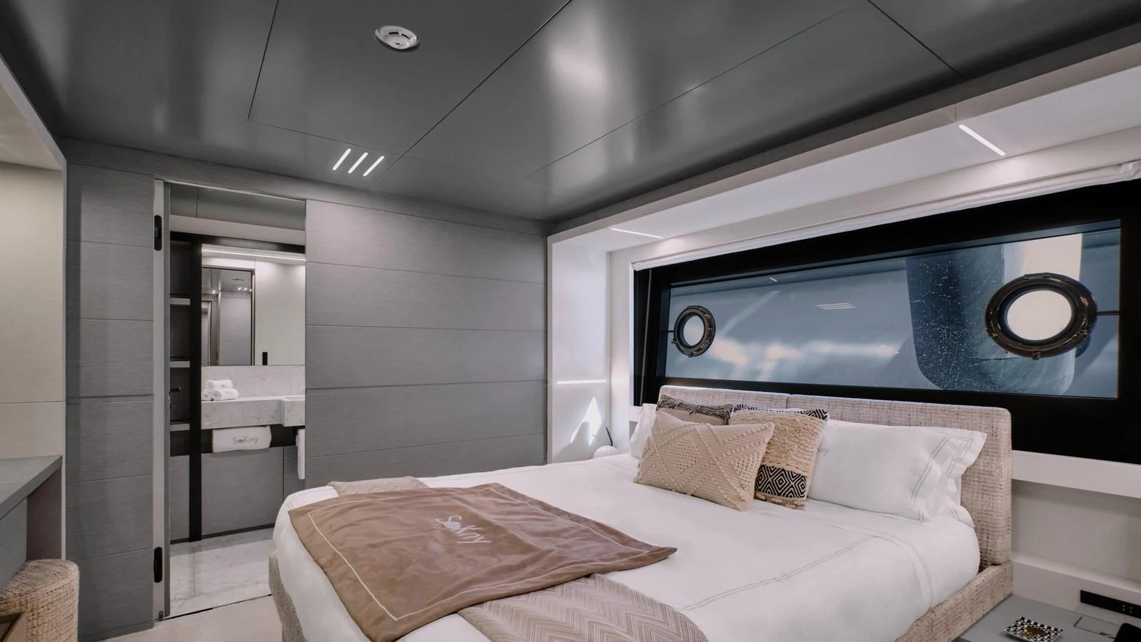 The stateroom features a luxurious bed with elegant bedding and a view of the sea through a large window. aboard BIZMAN Yacht for Sale