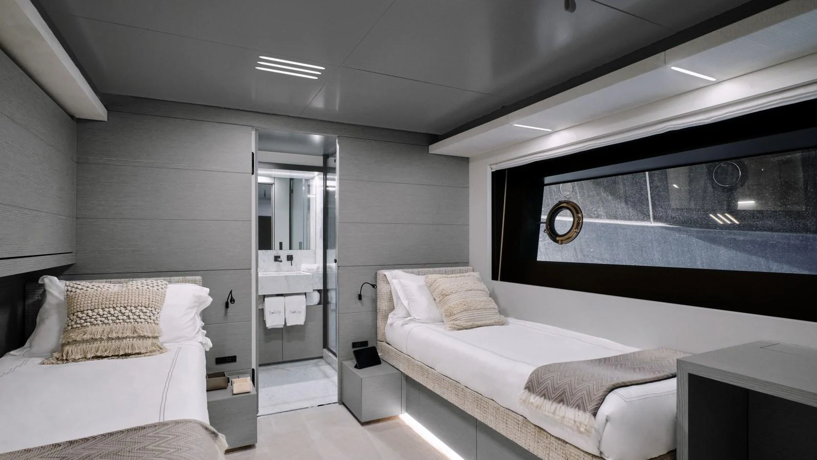 A modern guest stateroom featuring twin beds and an ensuite bathroom, designed with sleek lines and neutral tones. aboard BIZMAN Yacht for Sale