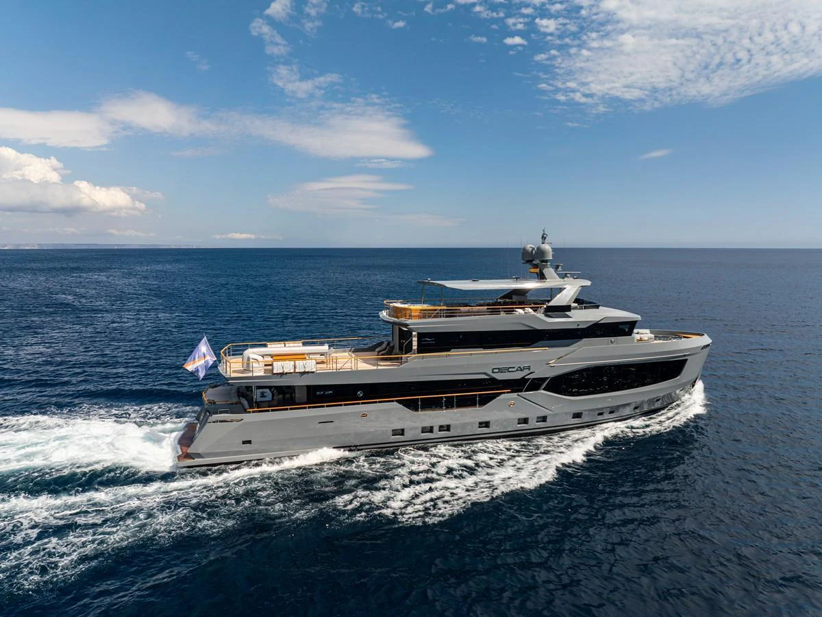 A sleek yacht cruises through the open sea under a clear sky. aboard OSCAR Yacht for Sale