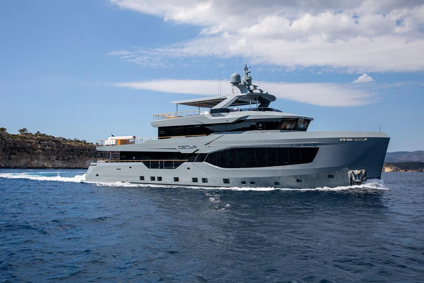 A sleek and modern yacht cruises gracefully on the open water under a partly cloudy sky. aboard OSCAR Yacht for Sale