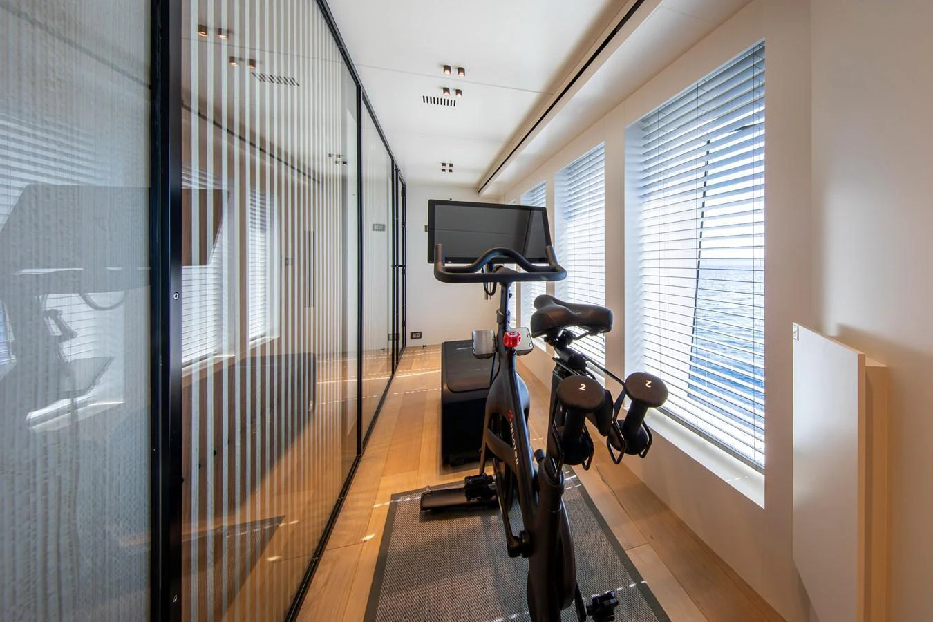 The yacht features a modern gym with a stationary bike and large windows for natural light. aboard OSCAR Yacht for Sale