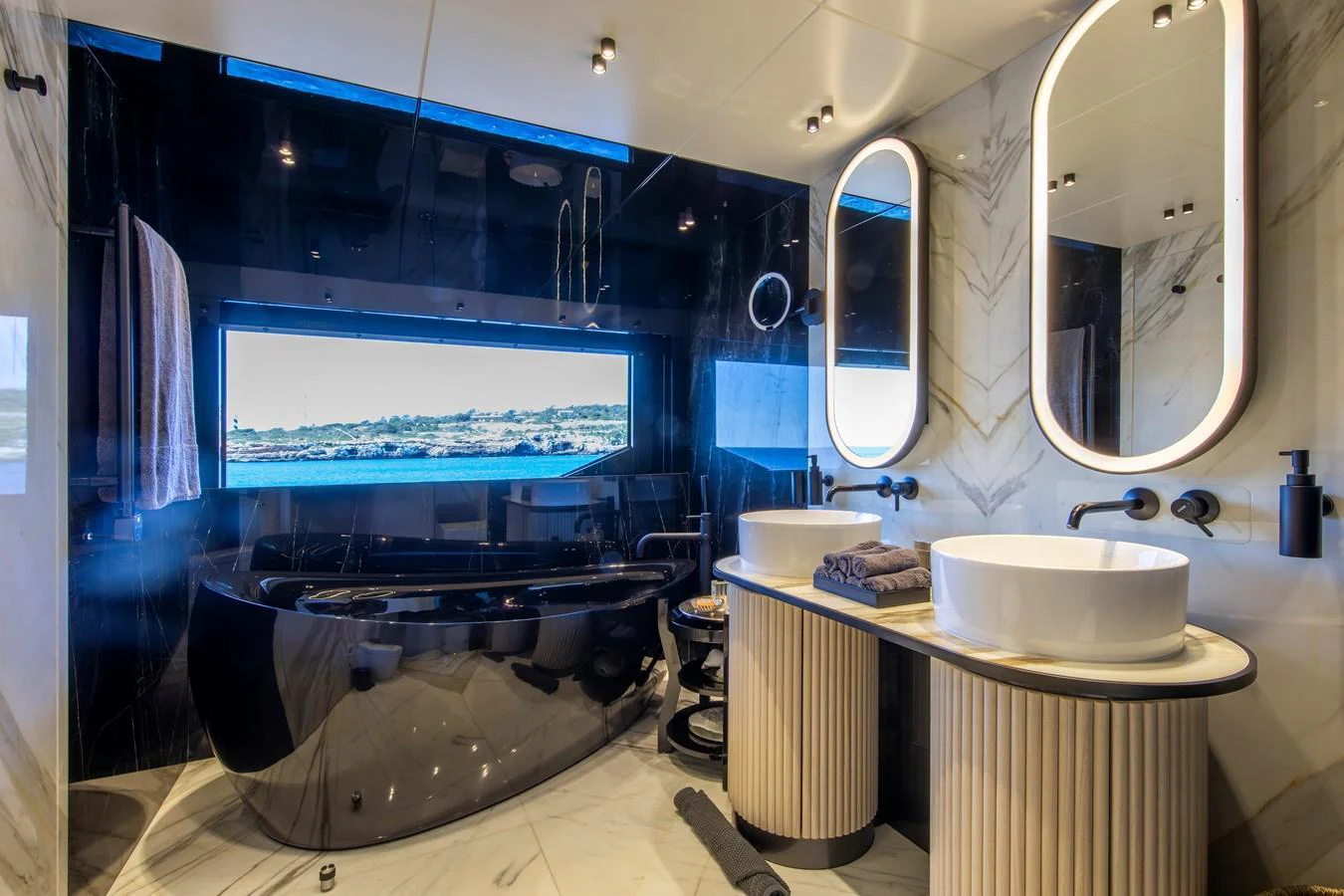A luxurious yacht bathroom featuring a sleek black bathtub and dual sinks with elegant mirrors. aboard OSCAR Yacht for Sale