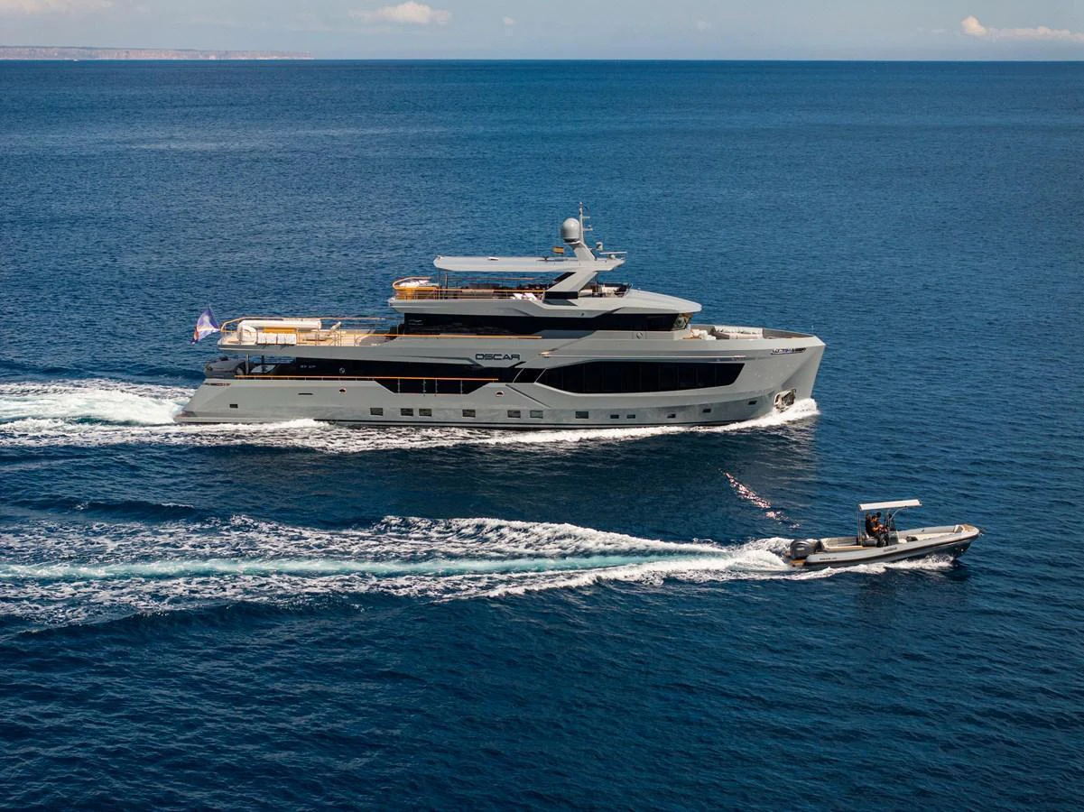 A sleek, modern yacht cruising on open waters accompanied by a tender. aboard OSCAR Yacht for Sale