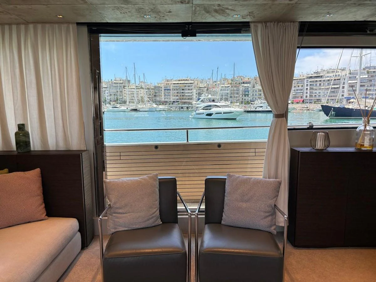 The yacht's interior offers a cozy seating area with a stunning view of the marina through large windows. aboard SL94 Yacht for Sale